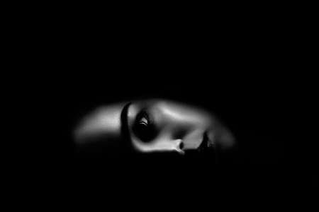 serious female face on back background with dramatic light, monochromeの写真素材
