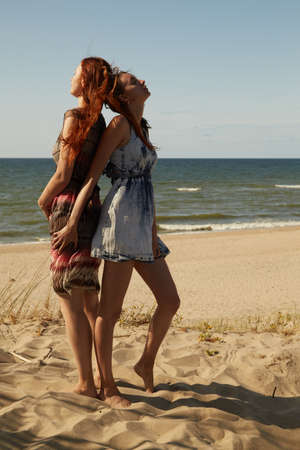 Two young women standing together on the beachの写真素材