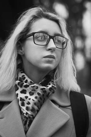sad young woman in eyeglasses looking aside, closeup portrait, monochromeの写真素材
