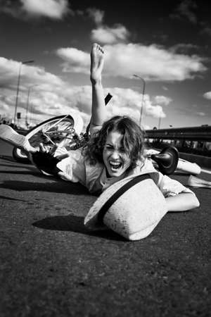 young woman fell from the bicycle, lies on asphalt shouts, monochromeの写真素材