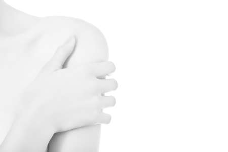 slim female hugging herself on white background with copy space, hand on bare shoulder closeup, monochromeの写真素材
