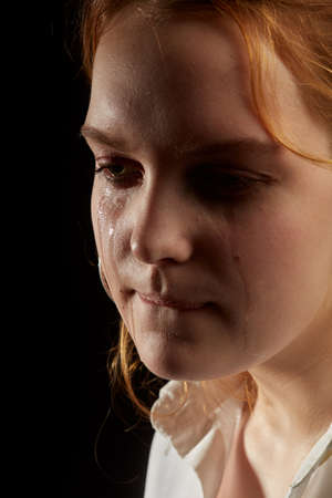 sad woman crying, looking aside on black background, closeup portraitの写真素材