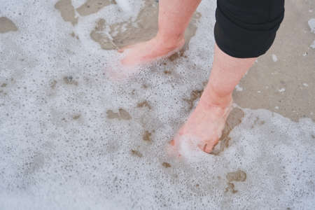 female bare feet stand in the water closeup top viewの写真素材