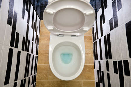 opened white toilet on a wooden floor close-up top view