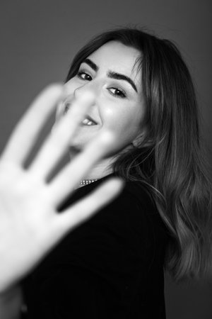 beautiful female portrait on gray background. young woman looking at camera laughing, monochromeの写真素材