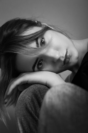 sad young woman looking at camera closeup portrait on gray background, monochrome