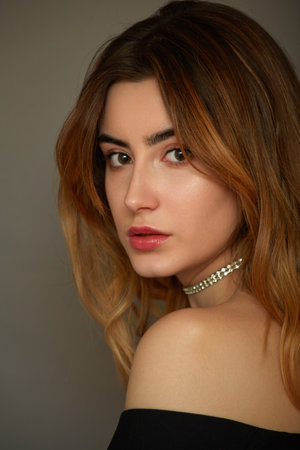 beautiful female portrait on gray background. young woman with bare shoulder looking at cameraの写真素材