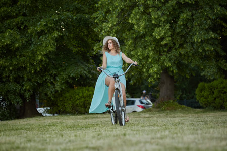 pretty woman biker on bicycle riding on green grass at parkの写真素材