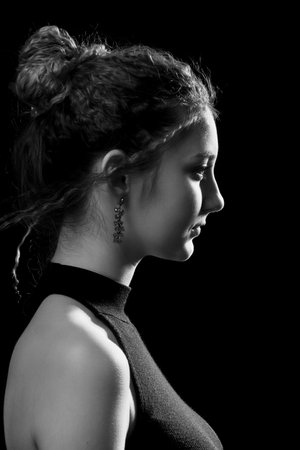 pretty young girl with flying curly hair closeup portrait profile side view on black background, monochromeの写真素材