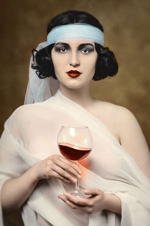 young woman in antic modern vintage retro style with red wine looking at cameraの写真素材