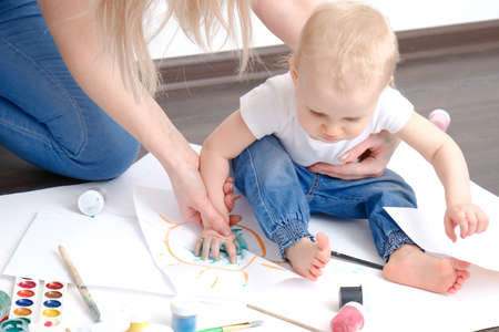young mom and her kid plays with watercolorsの写真素材