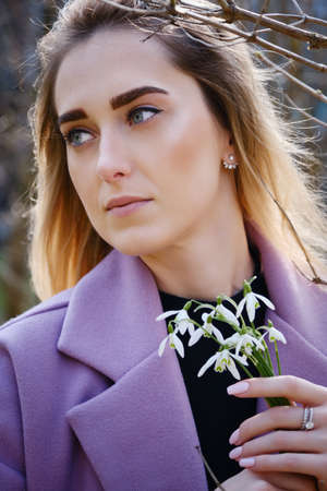 young blond woman with snowdrop bouquet at spring timeの写真素材