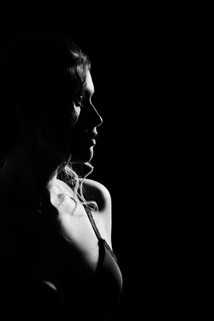 serious young woman on black background looking away side profile view monochromeの写真素材