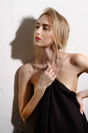 Luxury slim nude woman with black blanket posing near wallの写真素材