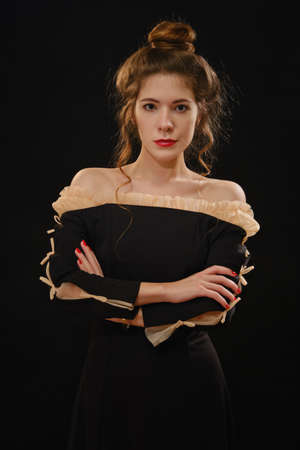 serious luxury young woman in black gothic dress on dark background looking at cameraの写真素材