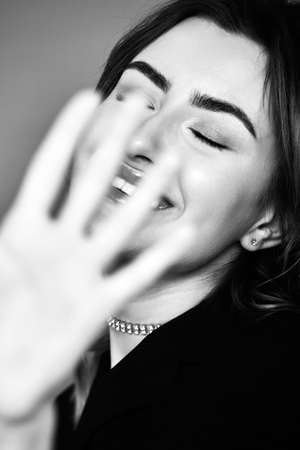 beautiful female portrait on gray background. the woman is fencing off the camera laughing, monochromeの写真素材