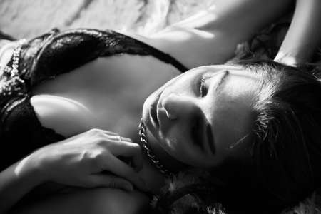 sensual beautiful woman lying in sunlight with blinds shadows, dreaming, monochromeの写真素材