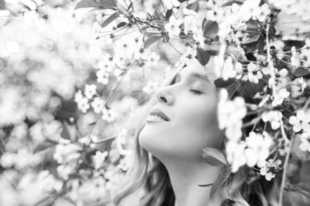 beautiful blonde woman near cherry blossoms close up portrait, monochrome