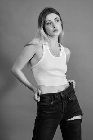 young woman in torn jeans stand on a gray background, monochromeの写真素材