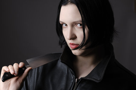 serious young woman with knife looking at camera closeup portrait