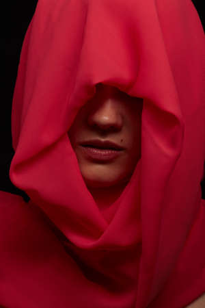 serious beautiful young woman with red headscarf over her face looking asideの写真素材