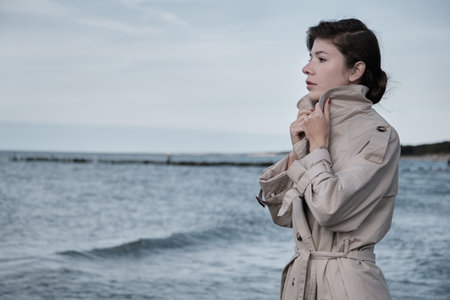 young luxury woman in coat near sea looking away profile viewの写真素材