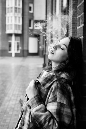 young woman on city street exhale smoke closeup portrait, monochromeの写真素材