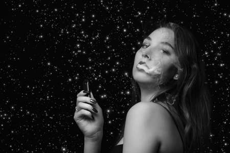woman blowing smoke on stars background, looking at camera, monochromeの写真素材