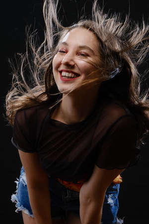 young happy woman in black hat looking at camera on black background, laughingの写真素材