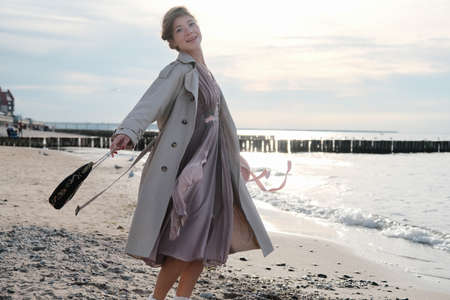happy young luxury woman near sea looking at camera dancingの写真素材