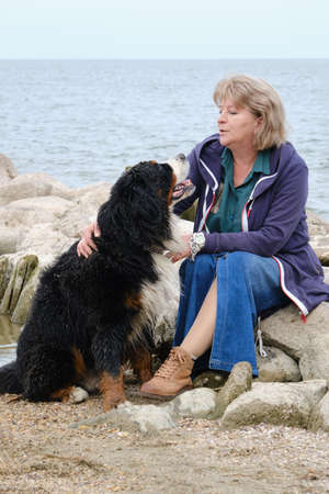 woman with dog on sea coast looking at him