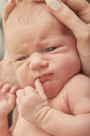 cute newborn girl lying on white fur looking at camera closeup portrait