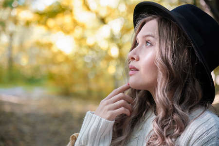 happy autumn woman posing in sunny park, looking away