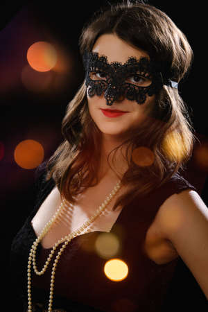 woman in carnival mask posing in studio on black background, smilingの写真素材