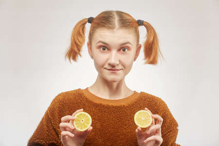 fun girl shows lemon on white background, grimacingの写真素材