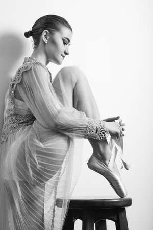 young beautiful ballerina puts on her shoes, monochromeの写真素材