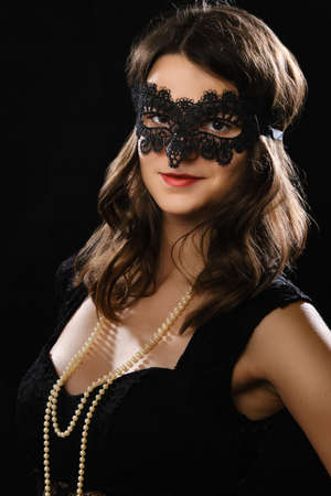 woman in carnival mask posing in studio on black background, smiling