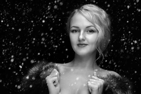 Beautiful woman in luxury fox fur, luxury retro vintage style with bare shoulders on snow background, monochromeの写真素材