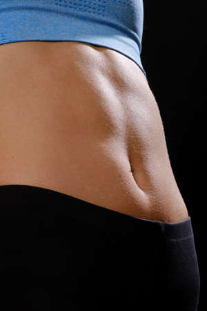 Abdomen of a slim woman closeup view on black background