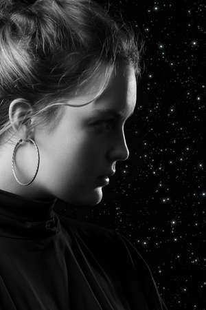 serious sad young woman with down syndrome on black background side profile view, monochrome