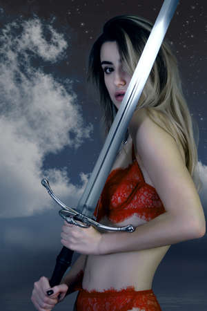 woman in red lingerie posing with sword on sky background in studioの写真素材