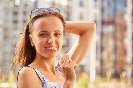 happy young woman with lollipop looking at camera