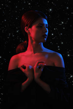 sensual serious woman in multicolor lights on stars background posing at studioの写真素材
