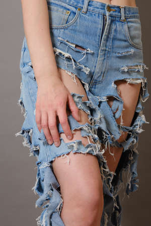beautiful slim female legs in ripped jeans close up