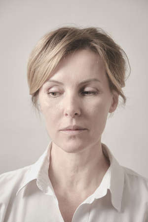 Senior woman in casuals looking aside serious. White background studio shot.