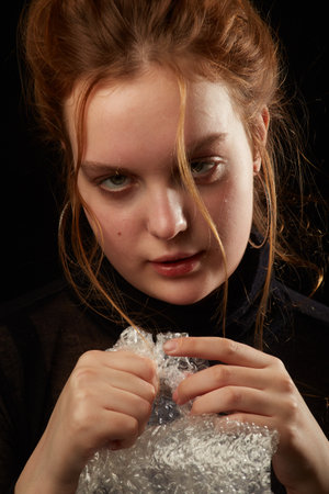 stressed woman in depression bursts bubbles of packaging cellophaneの写真素材