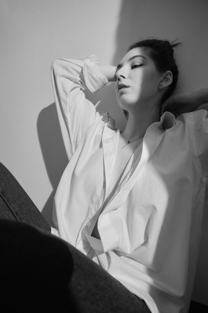 serious young woman feeling sad and scared, depressed. Sitting on white background with shadow monochromeの写真素材