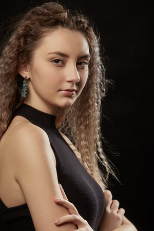 serious young girl with flying curly hair closeup portrait on black backgroundの写真素材