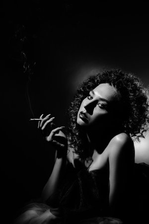 Close-up studio portrait of beautiful woman. Beautiful brunette model with long curly hair. Luxury makeup and bare shoulders monochromeの写真素材