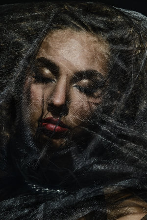 Close-up studio portrait of beautiful woman. Beautiful brunette model with black veil. Luxury makeup...